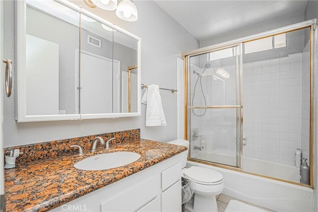 full bathroom with bath / shower combo with glass door, vanity, tile patterned floors, and toilet