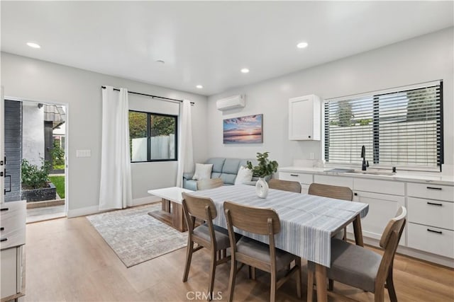 dining space featuring light hardwood / wood-style floors, sink, and a wall unit AC