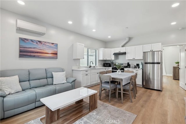 kitchen featuring an AC wall unit, white cabinetry, sink, stainless steel appliances, and light wood-type flooring