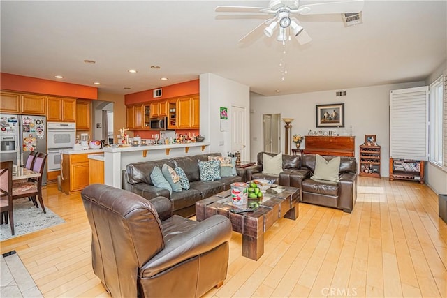 living room featuring ceiling fan and light hardwood / wood-style floors