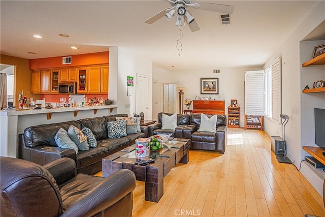 living room featuring ceiling fan, a fireplace, and light hardwood / wood-style floors