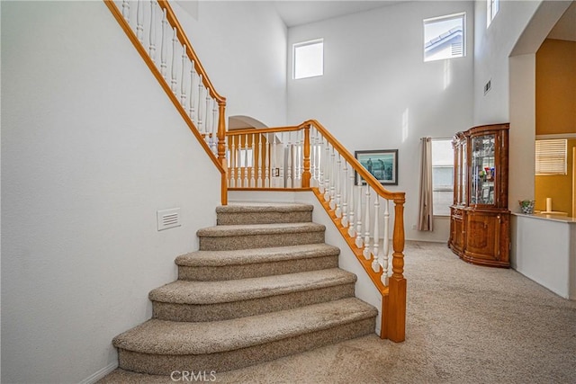 staircase with carpet and a high ceiling