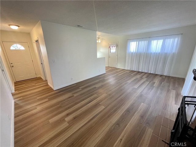 unfurnished living room with hardwood / wood-style flooring, ceiling fan, and a textured ceiling