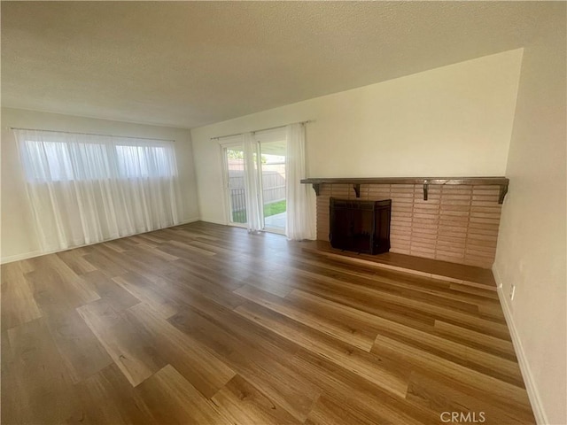 unfurnished living room with a fireplace, wood-type flooring, and a textured ceiling