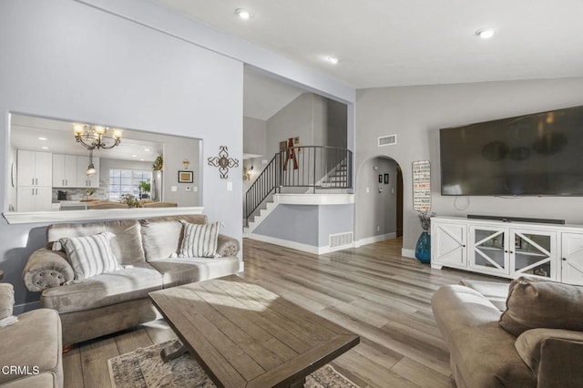 living room with a notable chandelier, light hardwood / wood-style floors, and high vaulted ceiling