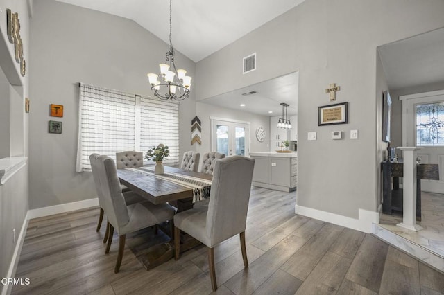 dining space featuring hardwood / wood-style floors, a notable chandelier, plenty of natural light, and high vaulted ceiling