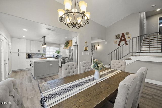 dining space with lofted ceiling, a chandelier, and light hardwood / wood-style flooring