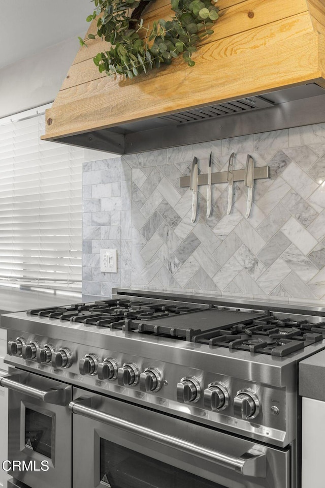 details featuring double oven range, decorative backsplash, and custom exhaust hood