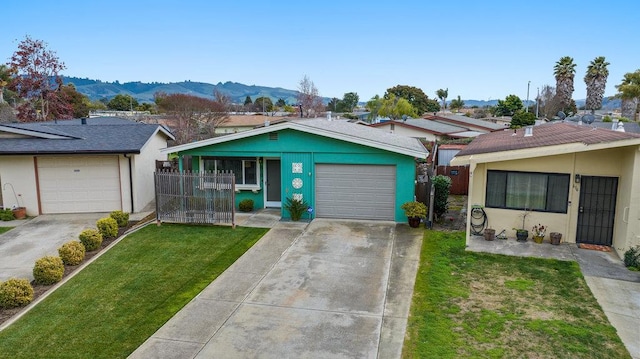 single story home with a garage, a mountain view, and a front yard