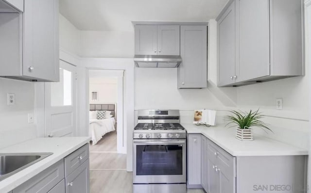 kitchen with light wood-type flooring, sink, stainless steel gas range oven, and gray cabinets