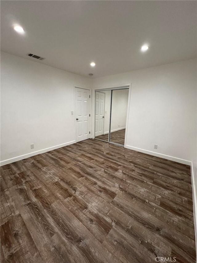 unfurnished bedroom with dark wood-type flooring and a closet