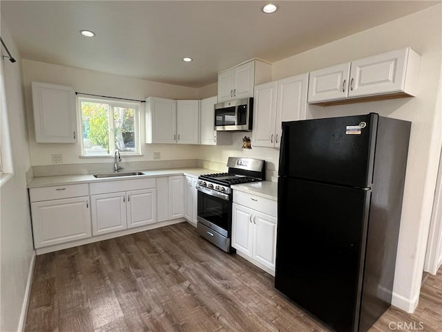 kitchen featuring appliances with stainless steel finishes, sink, white cabinets, and dark hardwood / wood-style flooring