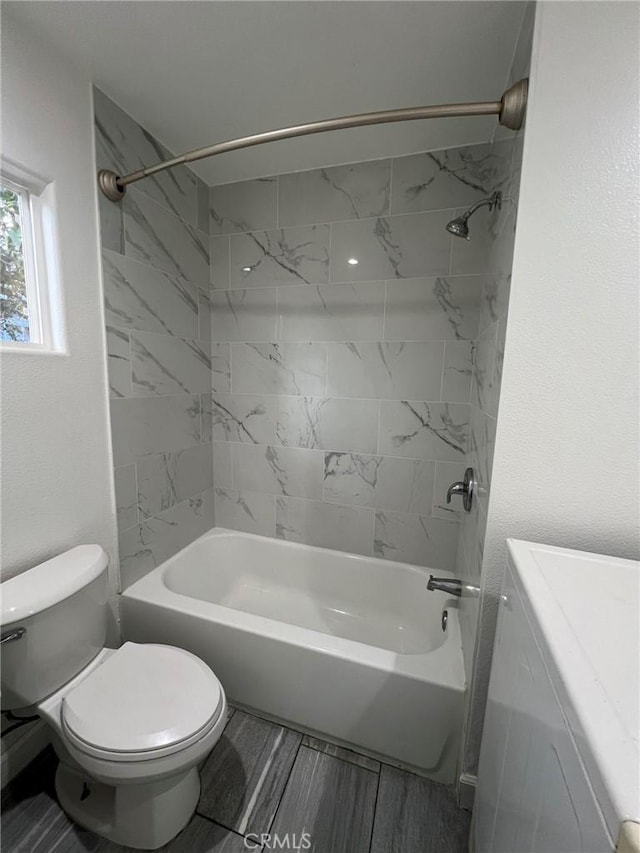 bathroom with toilet and tiled shower / bath combo