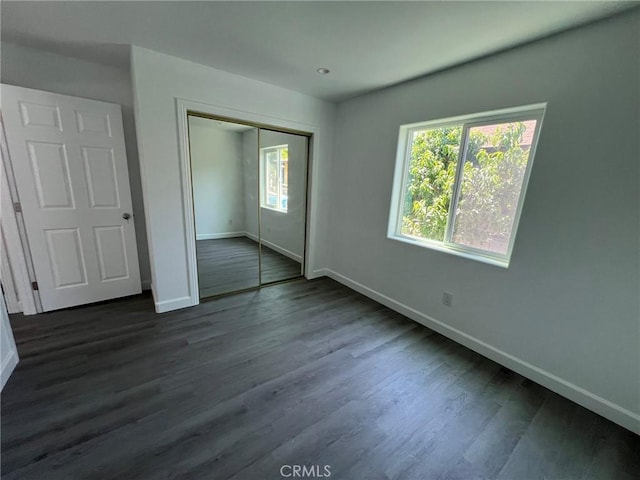 unfurnished bedroom featuring dark hardwood / wood-style flooring and a closet