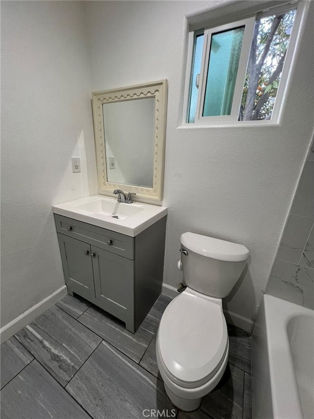 bathroom featuring vanity, a bath, and toilet