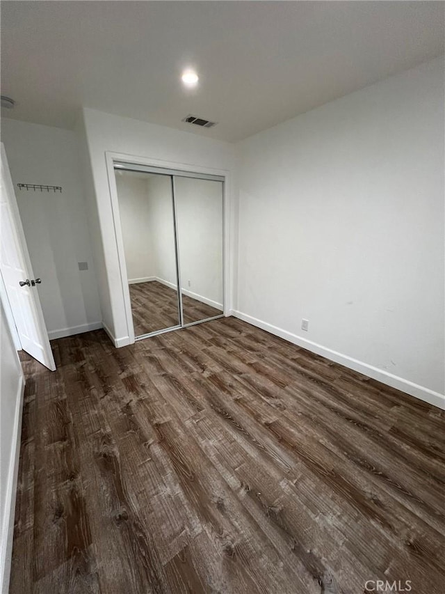 unfurnished bedroom featuring dark wood-type flooring and a closet