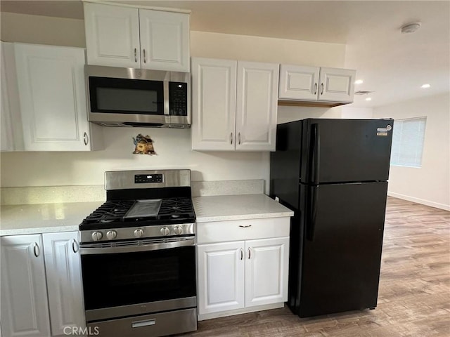 kitchen with white cabinetry, appliances with stainless steel finishes, and light hardwood / wood-style floors