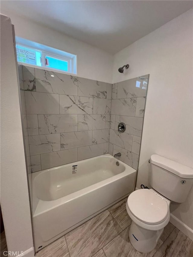 bathroom with tiled shower / bath combo and toilet