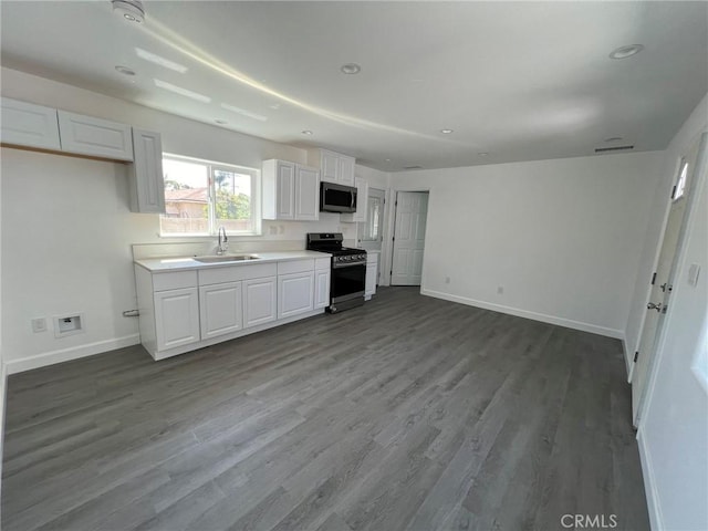 kitchen with sink, hardwood / wood-style flooring, white cabinets, and appliances with stainless steel finishes