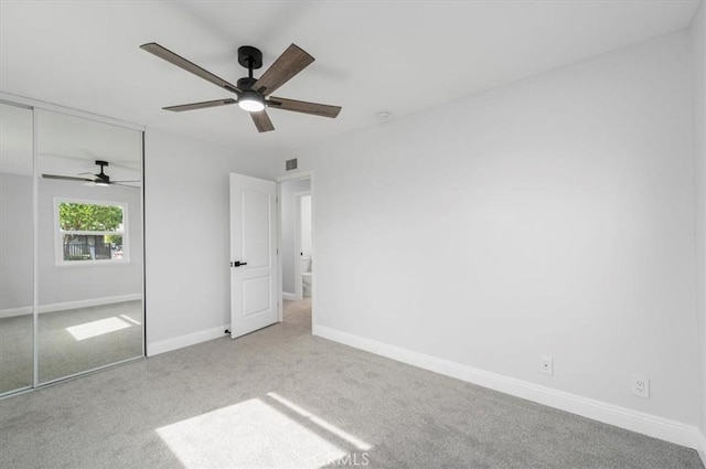 unfurnished bedroom with ceiling fan, light carpet, and a closet