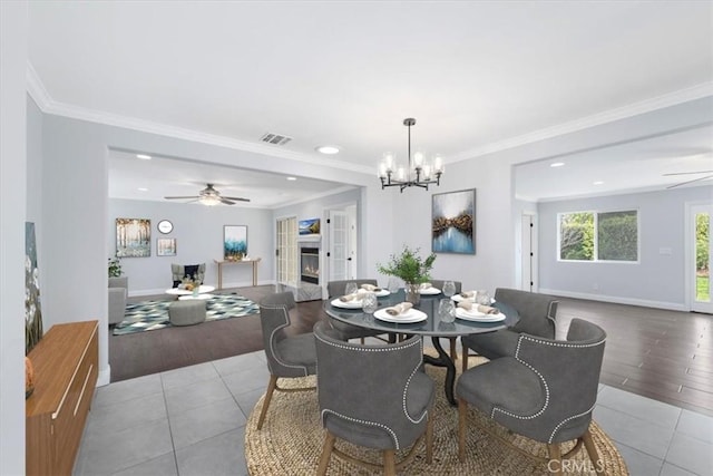 tiled dining space featuring crown molding and ceiling fan with notable chandelier