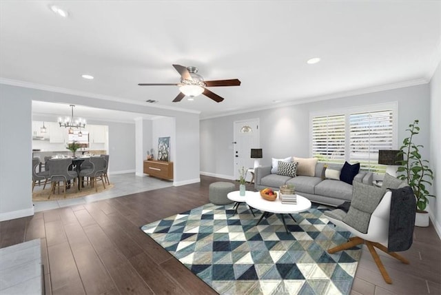 living room featuring ornamental molding, ceiling fan with notable chandelier, and dark hardwood / wood-style flooring