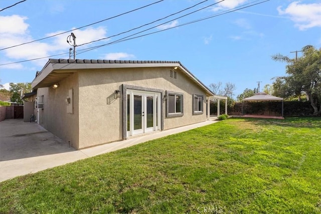 rear view of house featuring french doors, a patio area, and a lawn