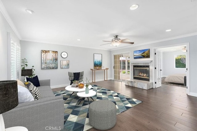 living room with ornamental molding, dark wood-type flooring, and ceiling fan