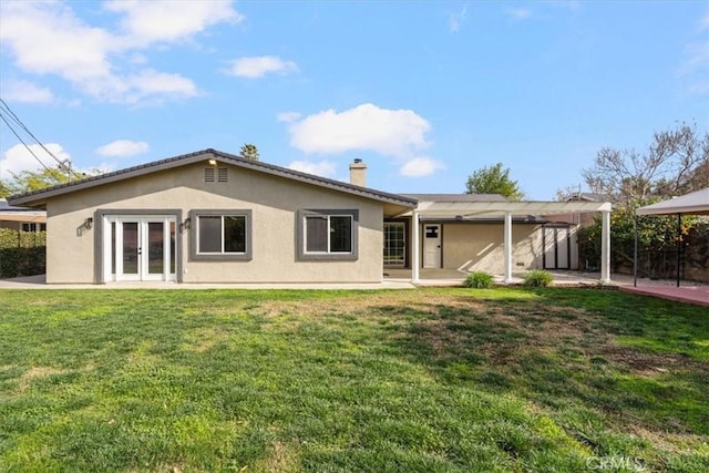 back of property with a yard, a patio area, and french doors