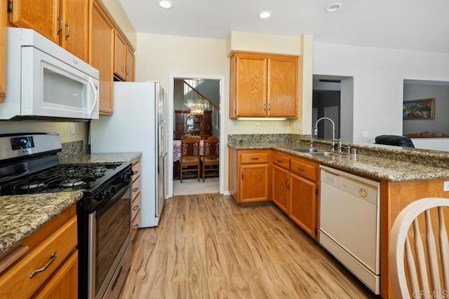 kitchen with light stone counters, sink, white appliances, and light hardwood / wood-style floors