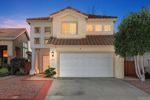 mediterranean / spanish-style house with driveway, a tile roof, a garage, and stucco siding