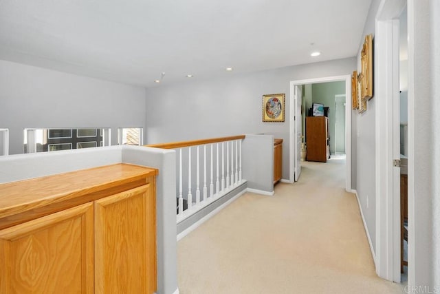 hallway with light carpet, recessed lighting, baseboards, and an upstairs landing