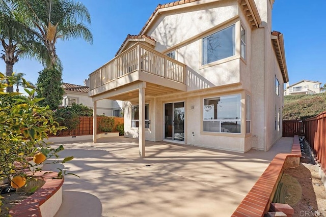 rear view of property with a balcony, a fenced backyard, and stucco siding