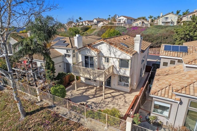 back of house featuring a tiled roof, a residential view, a chimney, and stucco siding