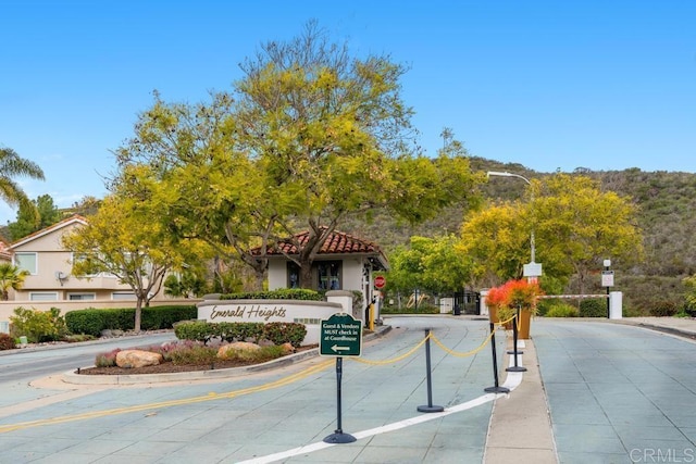 view of road with sidewalks, street lights, a gated entry, and curbs