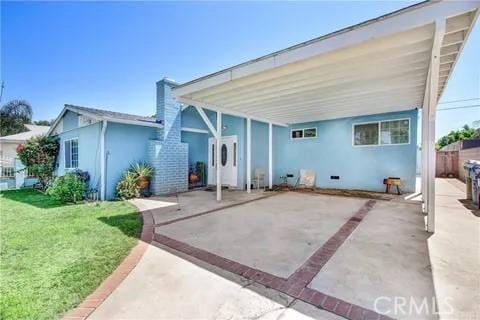 rear view of property featuring a carport and a lawn