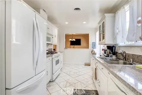 kitchen featuring light tile patterned flooring, sink, white cabinetry, white appliances, and light stone countertops