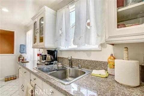 kitchen featuring white cabinetry, sink, and light tile patterned flooring