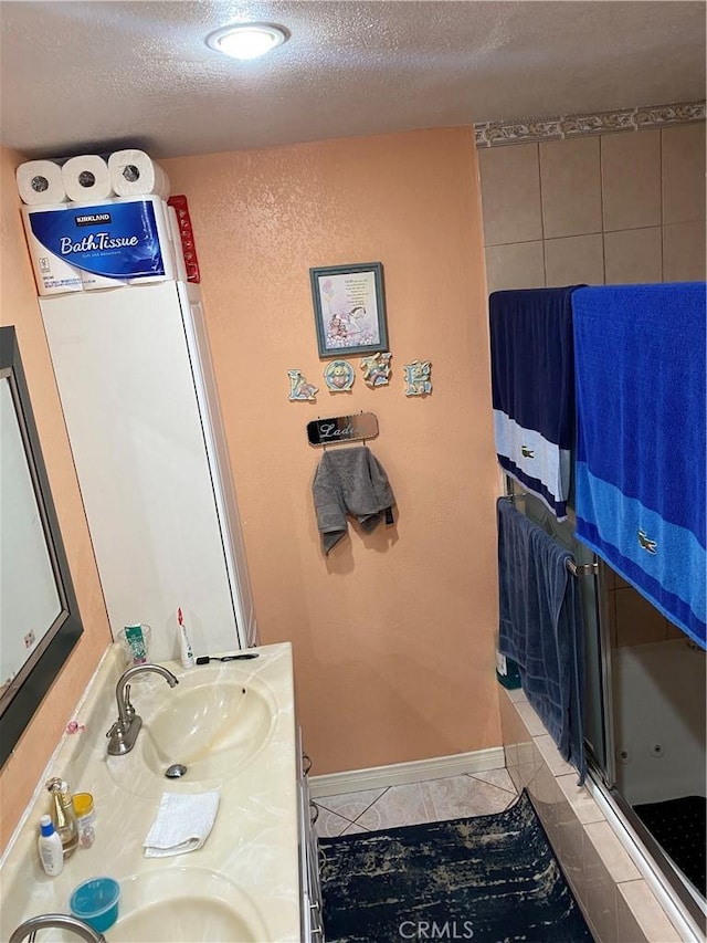 bathroom featuring tile patterned flooring, vanity, an enclosed shower, and a textured ceiling