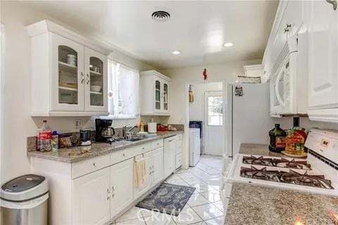 kitchen with white cabinetry, sink, white appliances, and light stone counters