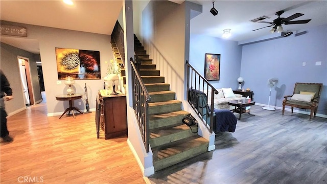 staircase featuring wood-type flooring and ceiling fan