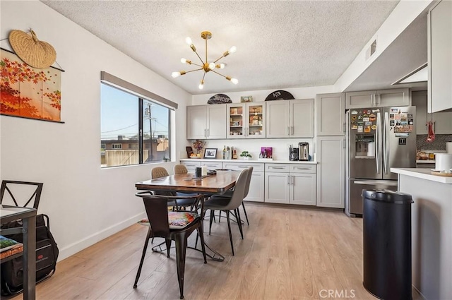 dining area with a notable chandelier, light hardwood / wood-style floors, and a textured ceiling