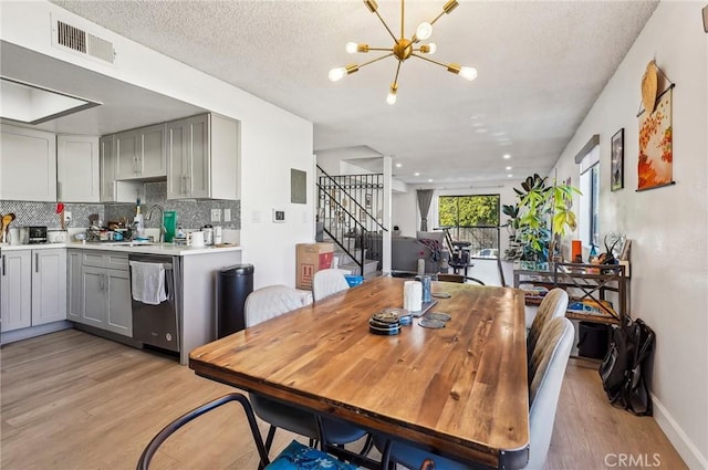 dining space featuring sink, an inviting chandelier, a textured ceiling, and light wood-type flooring