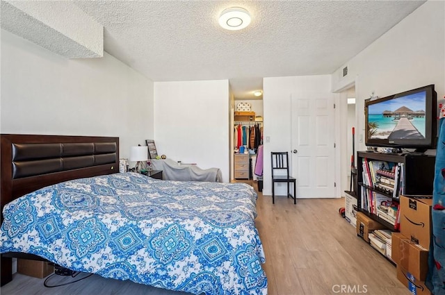 bedroom with a textured ceiling and light wood-type flooring