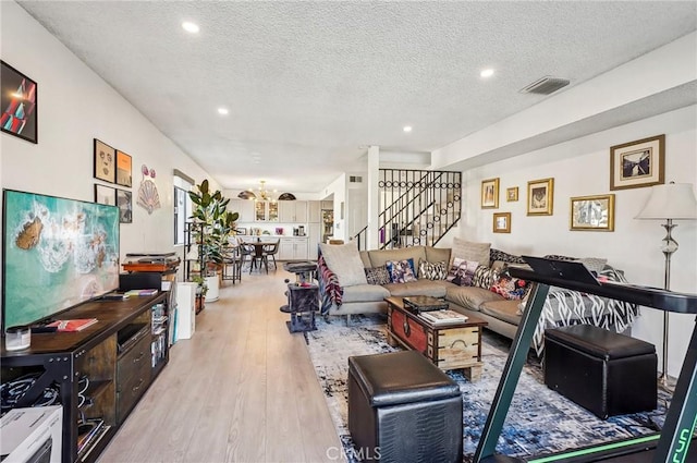 living room featuring a chandelier, a textured ceiling, and light wood-type flooring