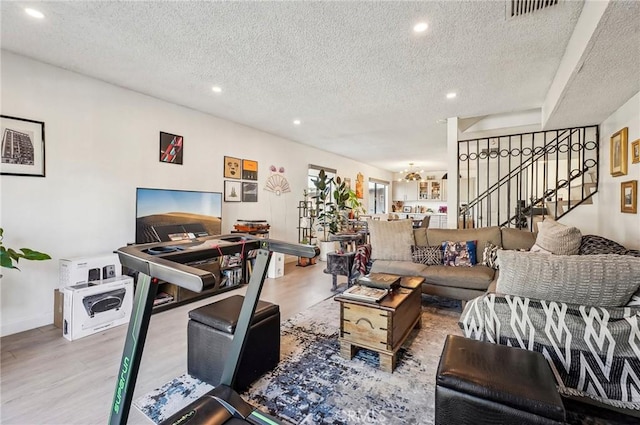 living room featuring a notable chandelier, light hardwood / wood-style flooring, and a textured ceiling