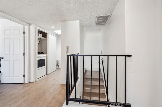 corridor with light hardwood / wood-style flooring and a textured ceiling