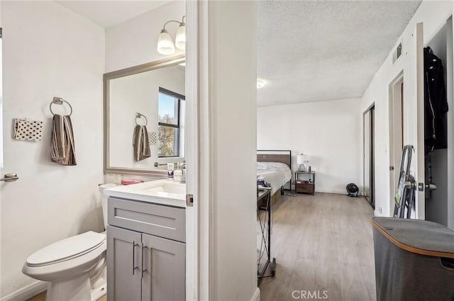 bathroom featuring vanity, toilet, hardwood / wood-style floors, and a textured ceiling