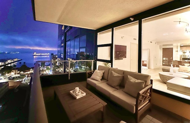 balcony at dusk featuring an outdoor hangout area and a water view