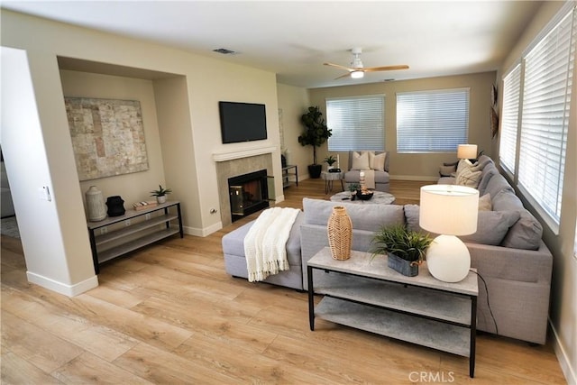 living room featuring ceiling fan, a fireplace, and light hardwood / wood-style floors